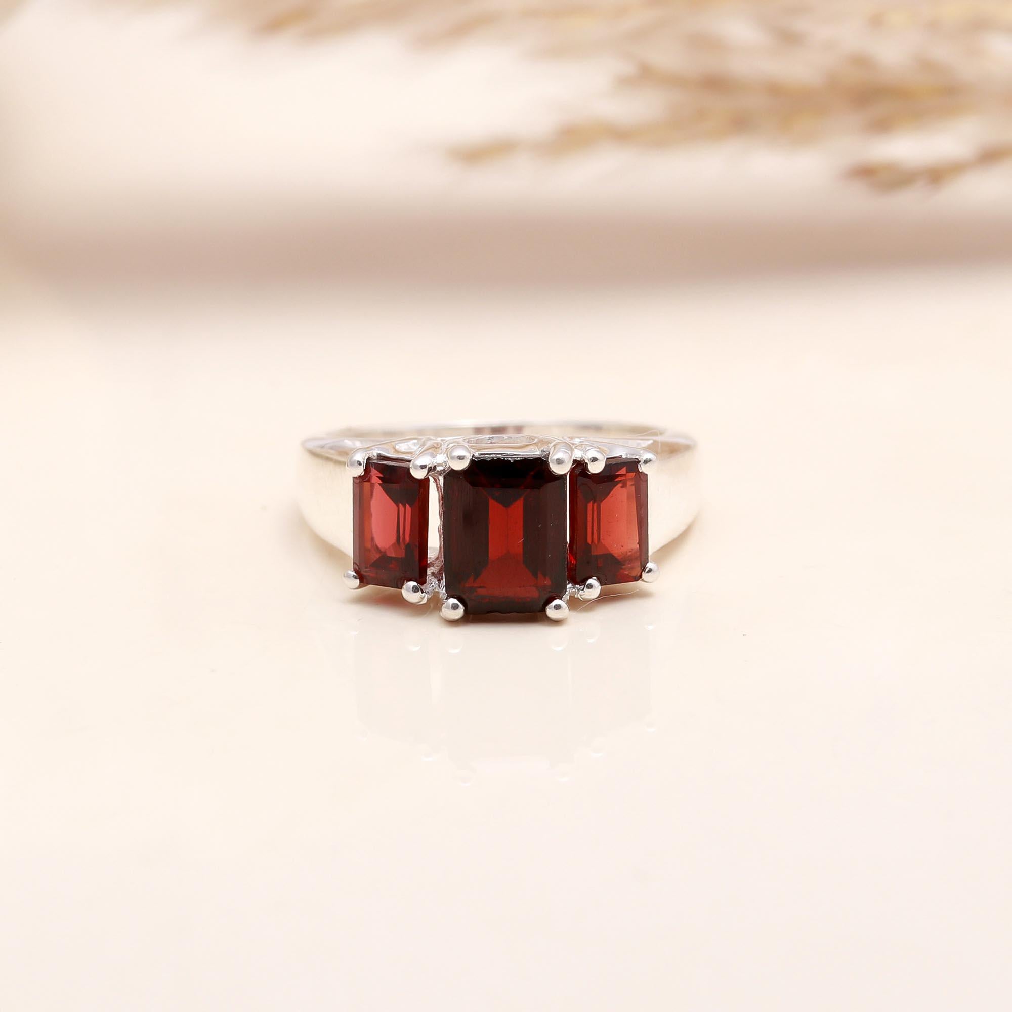 Emerald cut garnet three-stone sterling silver ring close-up