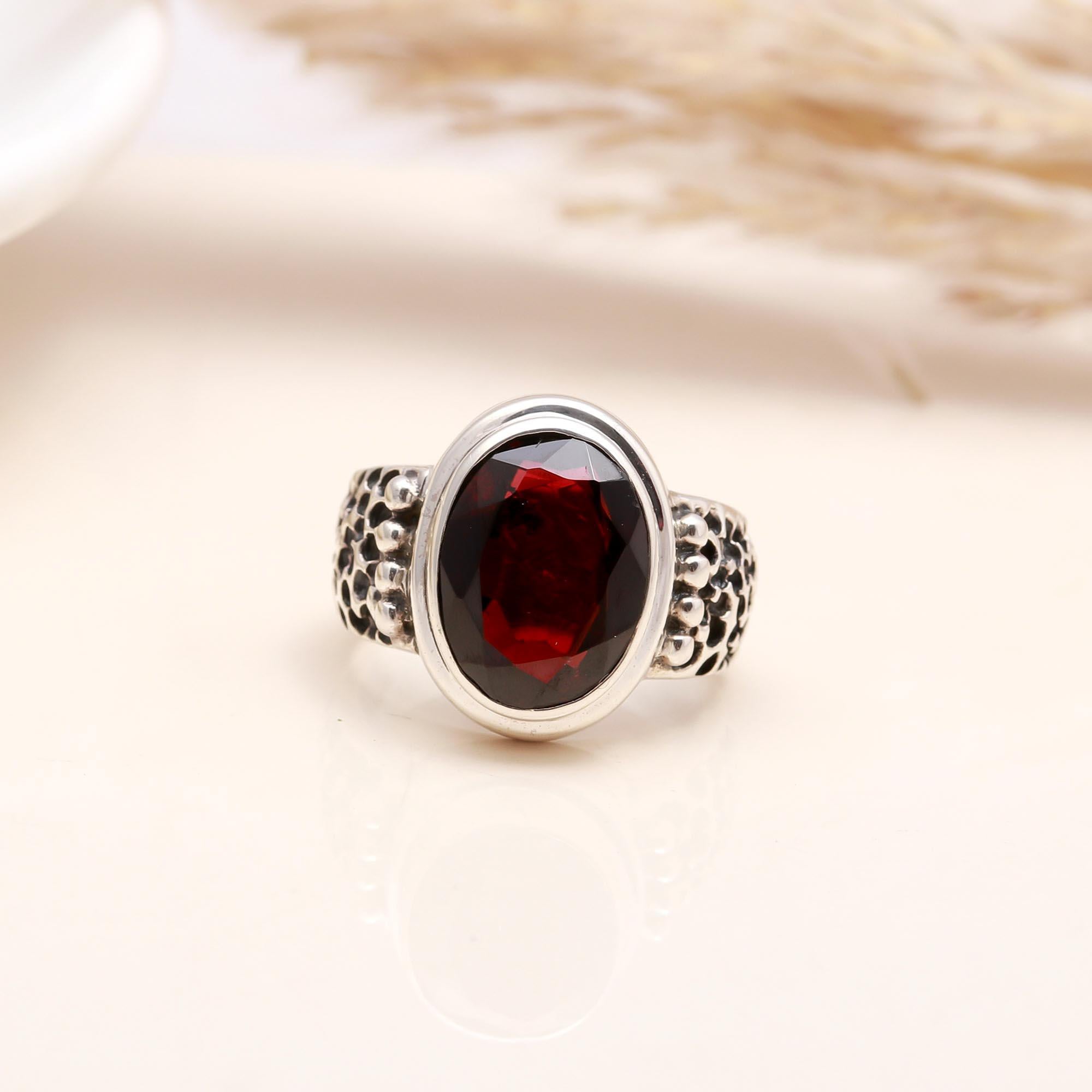 Close-up of oval garnet with textured silver band