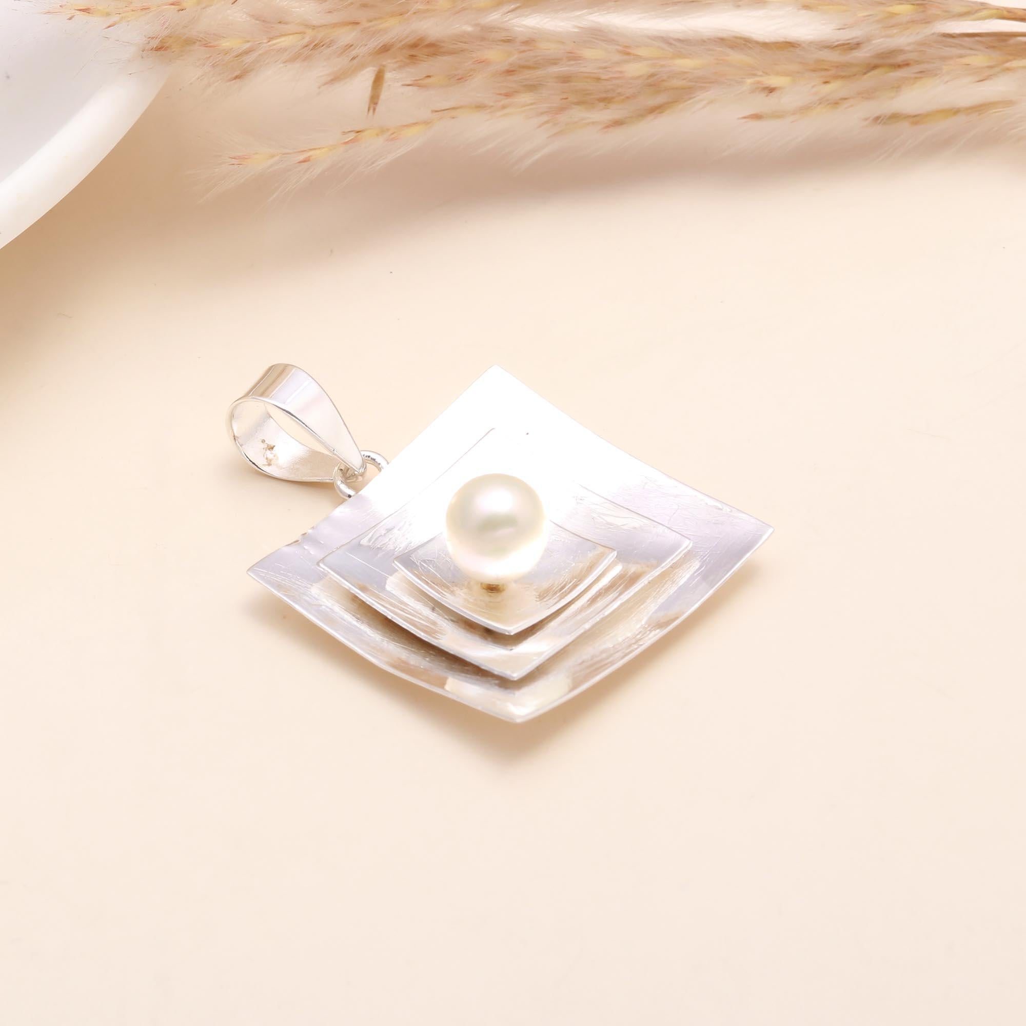 Sterling silver geometric pendant with white pearl centerpiece on a hand, modern square design.