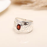 Detailed cutout filigree design on silver ring with garnet